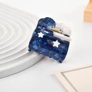 Détail macro d'une pince à cheveux en acétate avec motif marbré bleu et étoiles
