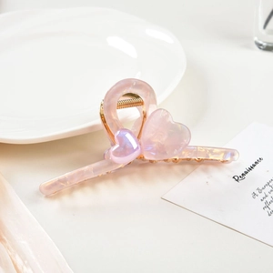 Detailed close-up of pink marble heart hair claw with golden metal spring structure