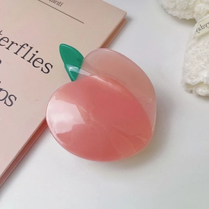 Dettaglio di un fermaglio per capelli a pesca realistico con sfumatura rosa e foglie verdi