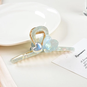 Detail of a light blue iridescent heart hair claw clip with golden metal springs