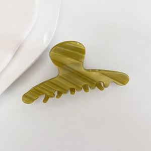 Close-up of olive green acetate hair claw clip with translucent shell texture on white