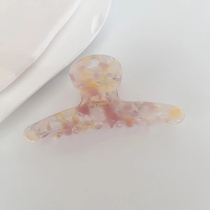 Detailed macro view of acetate claw clip with pink purple marble texture and golden text