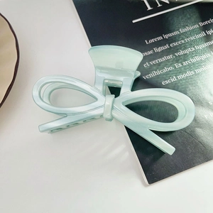 Détail d'une pince à cheveux nœud vert menthe posée sur un magazine de mode élégant