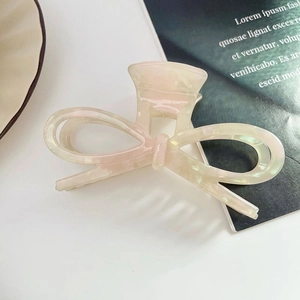 Détail d'une pince à cheveux papillon en acétate avec effet nacré sur un magazine