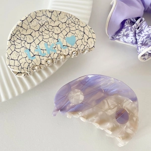 Detailed shot of marbled purple acetate hair claw clip and heart logo hair clip