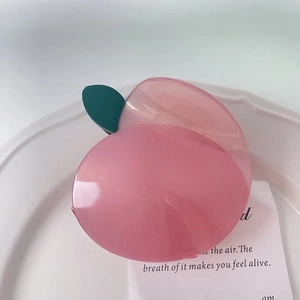 Vue détaillée d'une pince à cheveux pêche en acétate translucide de couleur rose doux