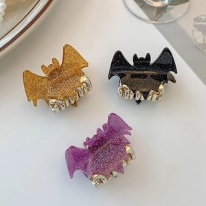 Detailed view of Halloween bat-shaped hair claws with glitter finish in gold, black and purple