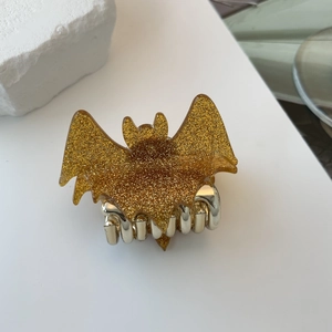 Macro view of gold-colored bat hair claw with sparkling glitter finish and metal teeth