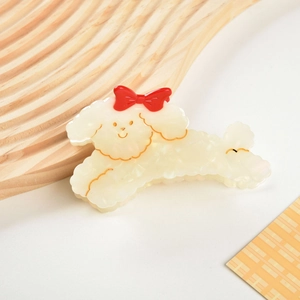 Detailed view of poodle hair claw clip made of pearlescent acetate with red bow