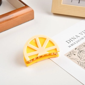 Detail of creative lemon slice hair claw clip with vibrant yellow acetate and gold metal teeth