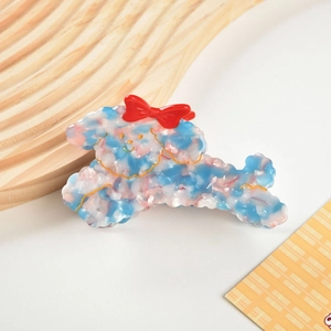 Macro view of poodle-shaped acetate hair claw with marble texture and red bow detail