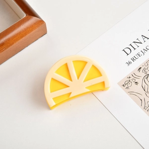 Detailed view of a lemon slice acetate hair claw clip with yellow and beige finish