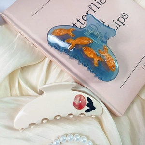 Elegant acetate hair claws with blue goldfish and white floral patterns on silk background