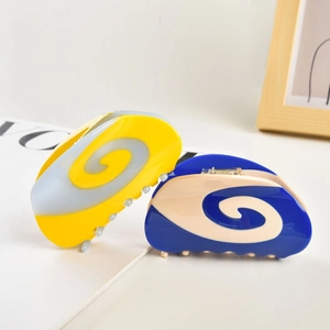 Macro detail of bicolored acetate hair claw clips with elegant glossy swirl patterns