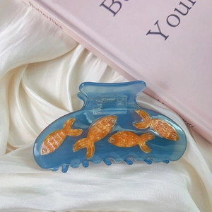 Close-up of blue resin hair claw clip with orange koi fish and rhinestone details