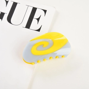 Detail view of macaron swirl hair claw clip in yellow and grey with glossy finish