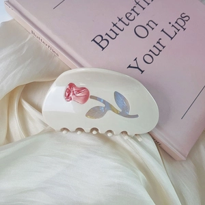 Close-up of cream acetate hair claw clip with metallic pink rose on silk fabric