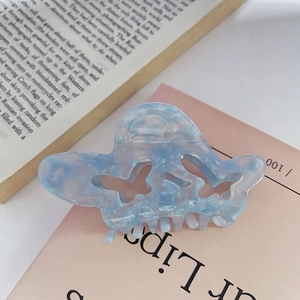 Dettaglio della molletta a farfalla in acetato azzurro con elegante texture marmorizzata