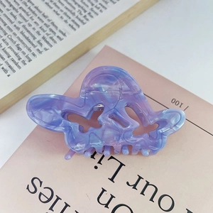Primo piano di una pinza per capelli a farfalla in acetato marmorizzato viola e blu
