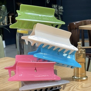 Set of large colorful acetate hair claws with Hold On engraving on a wooden table