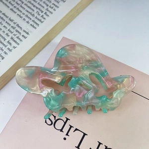 Dettaglio della molletta per capelli in acetato marmorizzato su sfondo di libro e luce