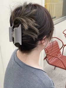 Detail view of a matte grey large hair claw clip with HOLDON lettering on hair