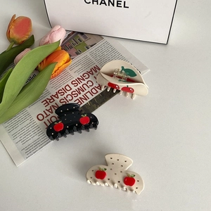 Detailed view of acetate hair claws featuring 3D red cherry patterns and crystal accents