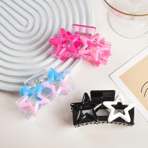Close-up of Y2K star hair claws in pink, blue, and black-white on a white tray