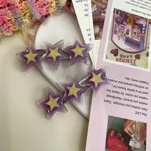 Détail de deux barrettes étoiles à paillettes mauves avec centre jaune sur assiette