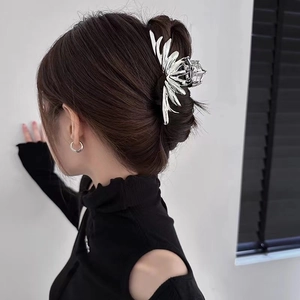 Silver metal irregular shark hair clip with radiant leaf design on a woman's hair bun