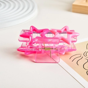 Detail of pink resin star hair claw clip with golden metal spring on aesthetic background