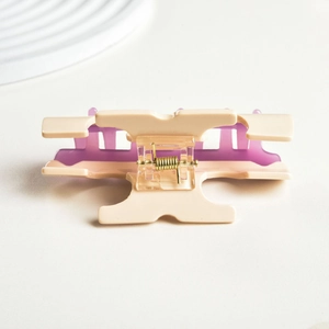 Detail of a two-tone acetate hair claw clip in cream and purple with a gold metal spring