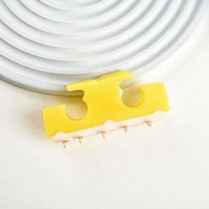 Close-up of yellow and cream bicolor acetate hair claw clip with glossy finish and wavy edge