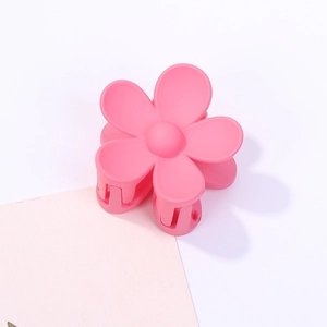 Dettaglio della molletta per capelli a fiore rosa opaco con design classico a cinque petali
