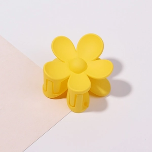 Dettaglio di una piccola pinza per capelli a fiore giallo opaco su sfondo bicolore