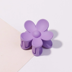 Dettaglio di un fermaglio per capelli a forma di fiore viola opaco con cinque petali su sfondo