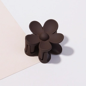 Dettaglio di un fermaglio per capelli opaco marrone caffè a forma di fiore con molla
