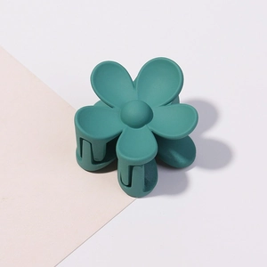 Dettaglio di una pinza per capelli a fiore verde foresta opaco su sfondo pastello minimale