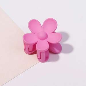 Dettaglio della piccola molletta per capelli a fiore rosa con trama opaca satinata