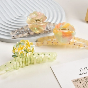 Detail of shell-shaped hair claws with marble texture and rhinestones in soft lighting