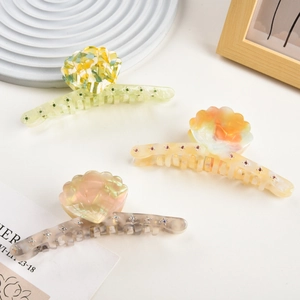 Detailed view of colorful acetate shell hair claws with rhinestones on a decorative tray