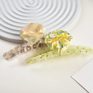 Detail of shell-shaped acetate hair claw clips featuring colorful rhinestones and pearly texture