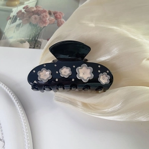 Detail view of black acetic acid hair claw with pink rhinestone petals and floral accents