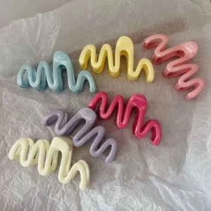 Set of six colorful wavy hair claw clips in cream, pink, and purple colors for women
