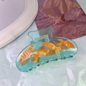Dettaglio della molletta per capelli in acetato blu con pesci rossi e piccoli strass