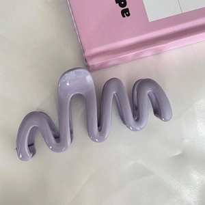 Close-up of a glossy lavender wavy hair claw clip on a soft pink and white background