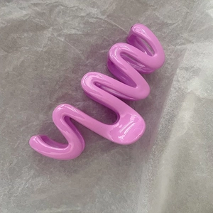 Detail view of a large wavy claw clip in a glossy lilac purple cream finish