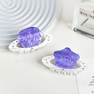 Close-up of elegant acetate hair claws with marble texture and sparkling rhinestones