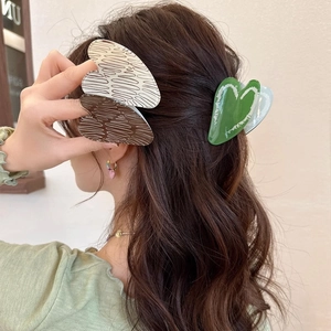 Elegant heart-shaped acrylic hair claw clips for women shown on long wavy hair