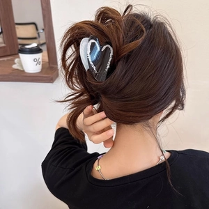 Minimalist heart-shaped acrylic hair claw clip with black and white patterns on model
